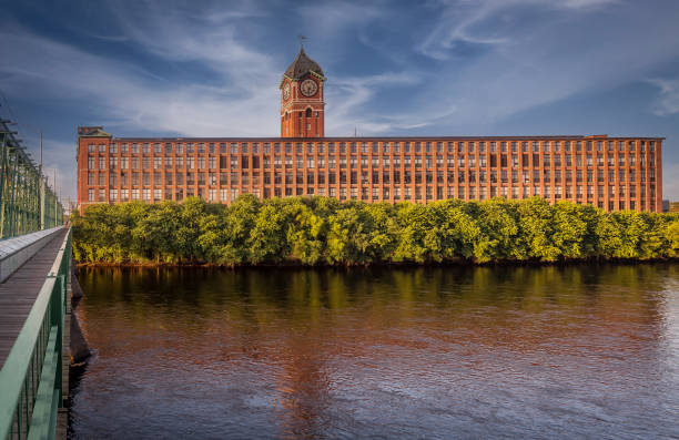 The Ayer Mill was established in the mid-19th century and was named after its founder, Frederick Ayer. The mill complex was part of Lawrence's thriving textile industry, which made the city an industrial hub in the 19th century. The mill operated during the height of the American Industrial Revolution and was a key player in the production of cotton textiles.\n\nThe Ayer Mill complex is known for its impressive and distinct architecture. It was designed to accommodate the large-scale machinery required for textile production. The buildings are often characterized by their red-brick construction, tall windows, and robust structural elements that reflect the industrial style of the era.\n\nThe building is now owned by New Balance.