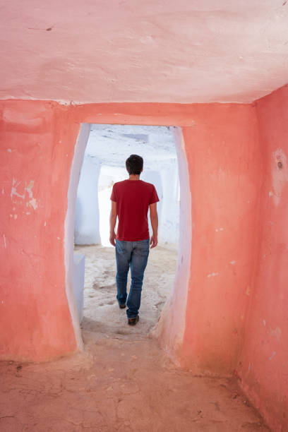 Man with red shirt walking inside abandoned Argueda caves, in Spain