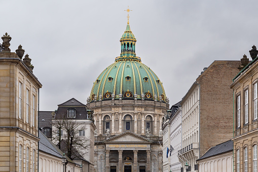 Dome of the royal palace in Copenhagen, a building with a large dome in green and gold tones that crowns a large white wall. Old building from the time of the royal houses
