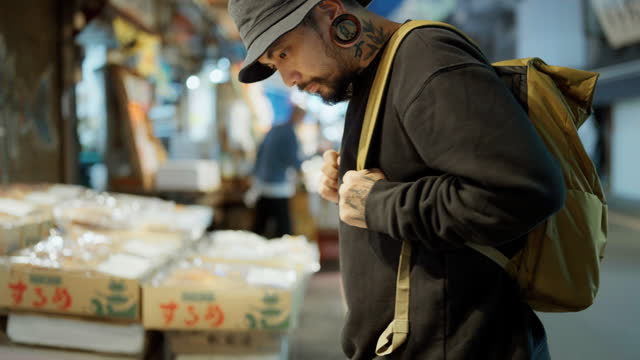 Asian man walking, looking around and buying food on street food at Tokyo, Japan.