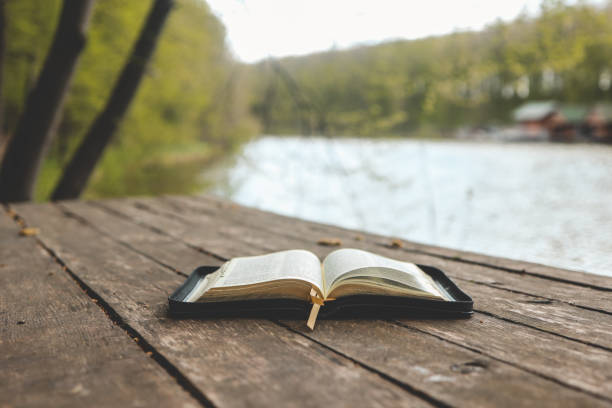 istock Open Bible on a wooden board near the river 1599149411