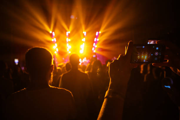 Hands holding phone and making photos on the concert. Concert background