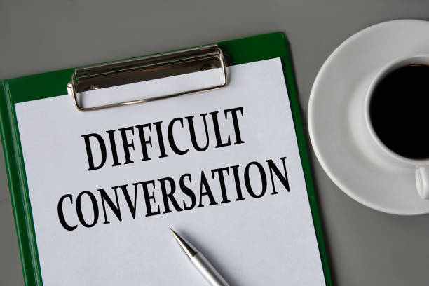 istock DIFFICULT CONVERSATION - words on a white sheet on a gray background with a pen and a cup of coffee 1599182798