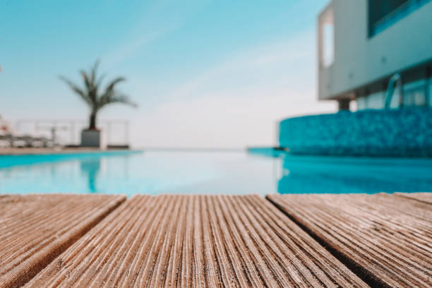 istock Empty wooden deck with swimming pool , Beautiful minimalist pool side view with clear blue sky . Vintage filter color apply 1599234414
