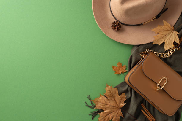 istock Versatile autumn accessories. Top view image displaying a stylish fedora, cozy scarf and a chic handbag on a dark green backdrop. Ideal for promoting everyday style. 1599302733