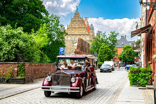 Torun, Poland - June 08, 2023: Vintage tourist guide car on the street on the historical district of Torun. Ancient Teutonic castle and medieval architecture. UNESCO world heritage site