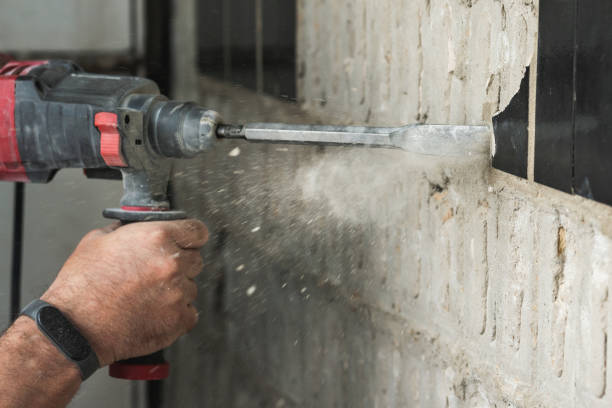 istock Builder with a puncher dismantles old tiles from a concrete wall 1599320940