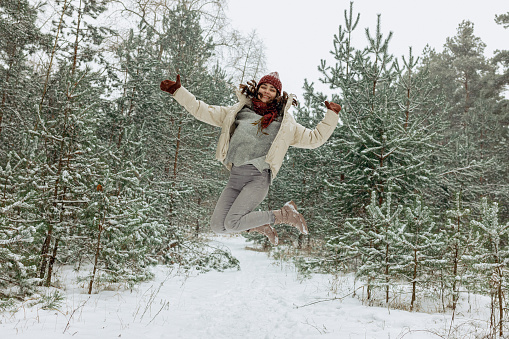 senior woman in white hat and fur coat enjoying winter in snow forest or park. Winter, age, season concept