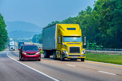 Horizontal shot of a yellow tractor trailer traveling on a Tennessee interstate highway.