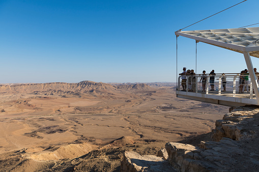 Mitzpe Ramon, Israel - August 5, 2023; People look out over the Ramon crater from the Suspended Balcony, or Lookout porch.