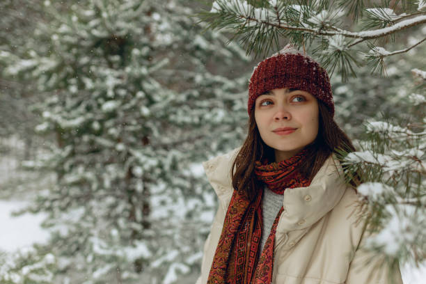 istock Smiling woman under snowy tree in winter woods 1599372813