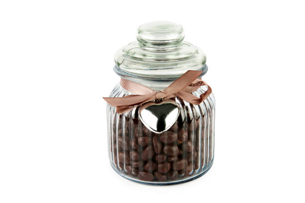 Chocolate dragee in transparent glass jar isolated on white background.