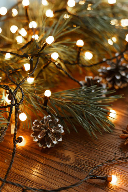 istock Christmas lights and spruce cones in wooden table 1599375544
