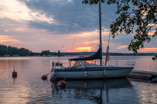Bright Sunset on Lake Saimaa Finland and a sailing yacht moored to the pier in the rays of the setting sun. summer landscape