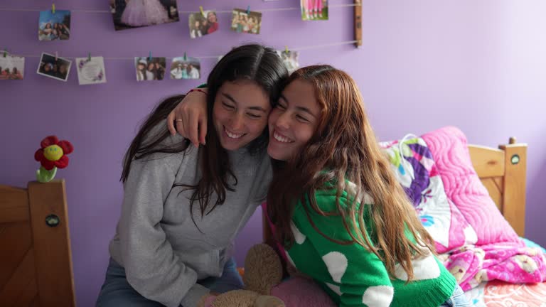 Young twin sisters remember good times with teddy bear on bedroom at home