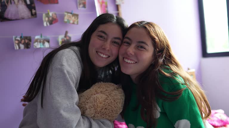 Portrait of young twin sisters remember good times with teddy bear on bedroom at home