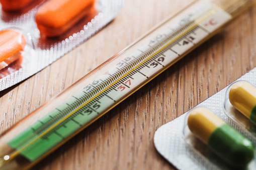 Medicines in a tablet and a thermometer close-up - bedside table during treatment for a cold