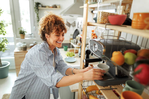 istock Young beautiful smiling woman making coffee in a domestic kitchen 1599452872