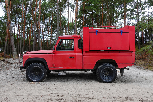 Leba, Poland - 31 July, 2023: Land Rover Defender in pick-up version parked on a road in a forest. This vehicle is used to get in extremely hard areas.