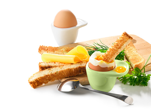 Soft boiled egg in an eggcup with toast and cheese on breakfast on white background