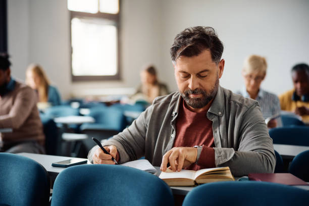 istock Mature man studying while attending adult education training class in the classroom. 1599475273