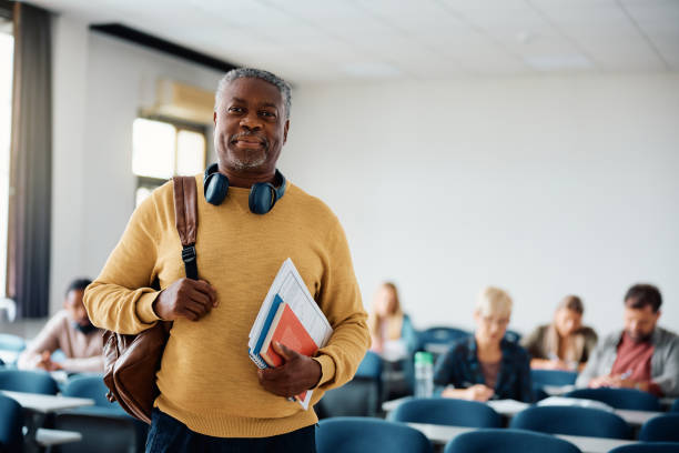 istock Smiling black senior man attending a class in lecture hall and looking at camera. 1599475481