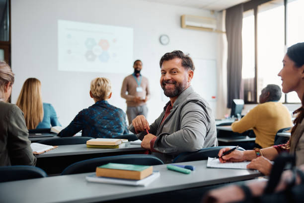 istock Happy mature man on education training class in lecture hall looking at camera 1599476351