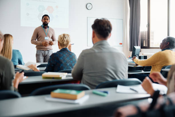 istock Black teacher talking to adult students during education training class in lecture hall. 1599476353
