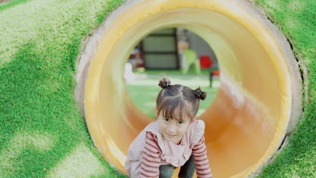 Preschool mixed Asian girl having fun on Montessori school playground, fun outdoor activity