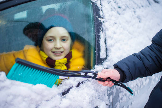 chłopiec patrzy przez okno ośnieżonego samochodu, czekając, aż tata zimą usunie śnieg ze szyby. skup się na brudnym szkle samochodowym - snow car window ice scraper zdjęcia i obrazy z banku zdjęć