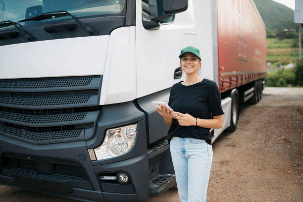 porträt einer jungen truckerin mit digitalem tablet, die neben ihrem truck steht - computer manual worker truck driver truck stock-fotos und bilder