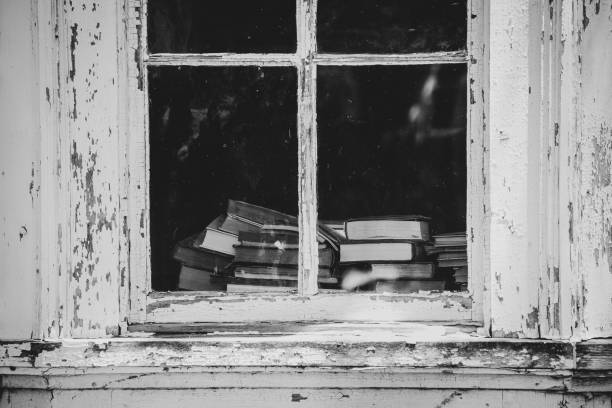 istock Stack of vintage books seen through window in old house 1599574969