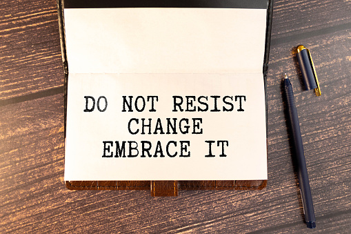 Do not resist change embrace it text on paper with wihte clip. On black background.