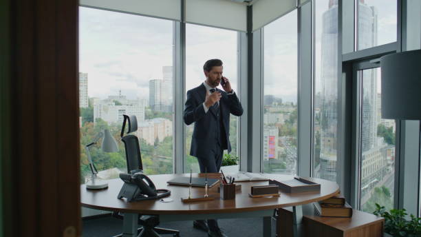 istock Annoyed entrepreneur talking phone gesturing emotionally standing modern office 1599701351