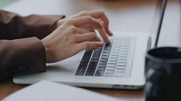 istock Woman hands typing laptop on table close up. Unknown girl working computer. 1599744384