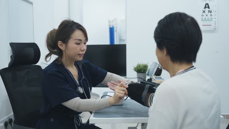 Asian chinese doctor measuring senior woman's blood pressure in clinic