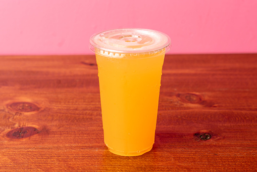 Stock photo showing close-up view of a glass jug containing lemon and lime juice with lime citrus fruit slices, ice cubes and crushed ice slushy covered in condensation showing the cold temperature of the beverage.