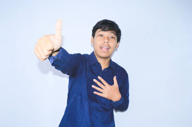 istock proud young asian man smiling with grateful face for survived from heart attack and has recovery is holding chest with thunbs up wearing navy shirt 1599873109