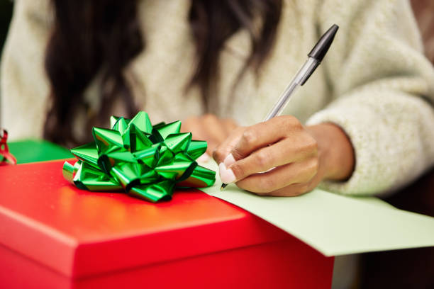 donna, mani e scrittura su regalo di natale, biglietto o lettera a sorpresa, festività o vacanze di dicembre. mano della persona femminile con carta e penna sul regalo o scatola con nastro per il pacchetto in casa - welcome sign greeting letter ribbon foto e immagini stock