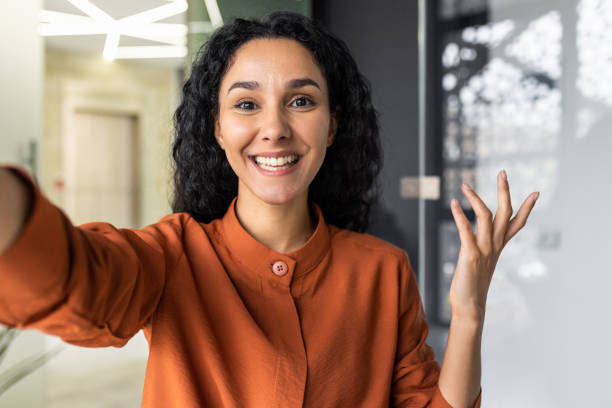 istock Video call from office hispanic business woman working inside modern office building, talking remotely with friends using app on phone for video call. 1599879738