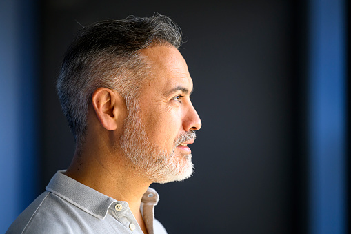 Profile of a mature businessman with gray beard and blank expression
