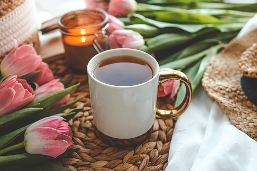 Beautiful spring composition, a cup of tea, tulips, a candle and a hat.