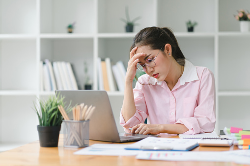 Professional millennial Accountant Woman in casuals working on financial analysis documents with a tense expression in the office