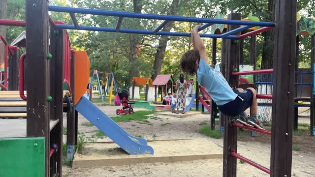Child playing climbing outdoor playground, happy preschool little kid having funny while playing climbs on a metal climbing ladder on playground equipment in daytime in summer, Little boy. 4k footage.