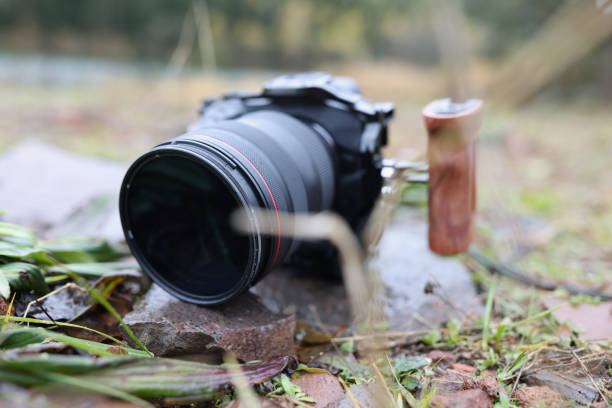 istock Black professional camera lying on ground near grass closeup 1600093576