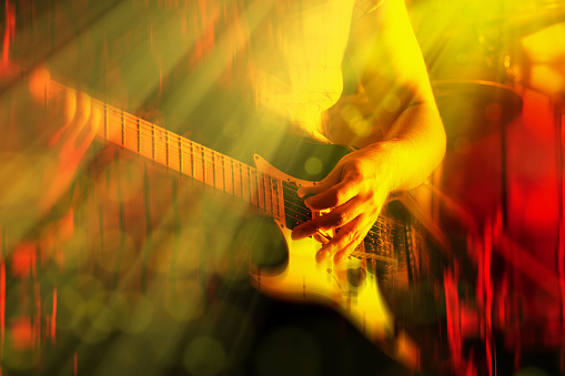 Cropped shot of electric guitar player playing hard rock music on stage