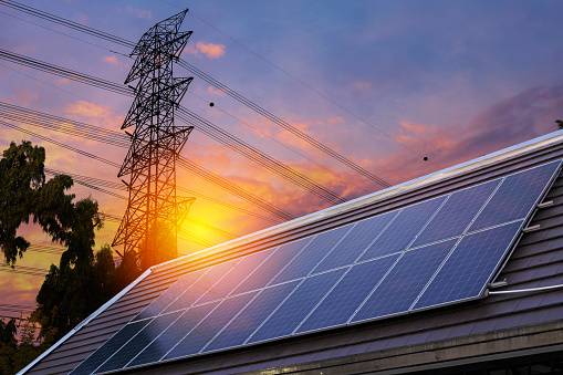 Solar panel on the roof, electrical wires on the rear background, alternative energy. Solar cells with radiation ot the sun and power pole. Power generation through solar energy