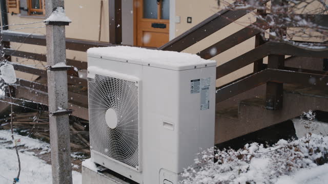 WS Snow falling over an external heat exchanger of an air-source heat pump