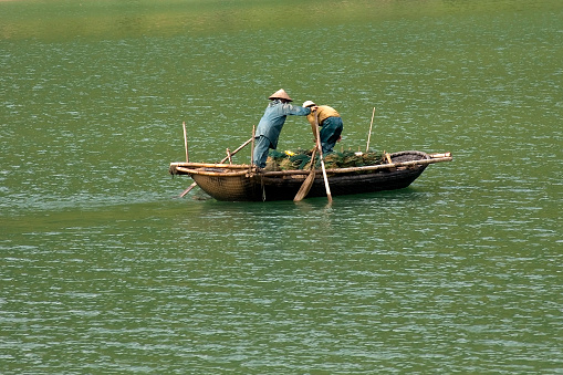 Vietnam, Asia- August 20,2023:A small fishing boat motoring in a calm sea in Halong Bay with misty limestone karsts behind Vietnam