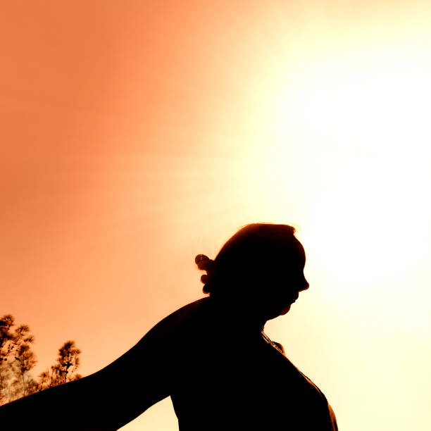 Close up silhouetted woman over shining sun